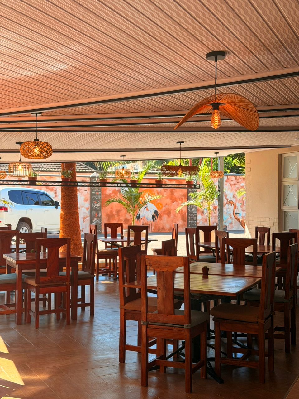 Interior dining area with bird mural, leaf pendant lights, and wooden furniture